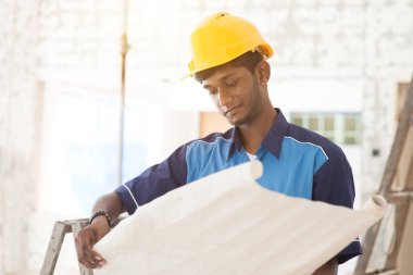 İnşaat işçisi planlara bakıyor.