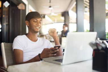 Smartphone ve dizüstü bilgisayar kullanan adam