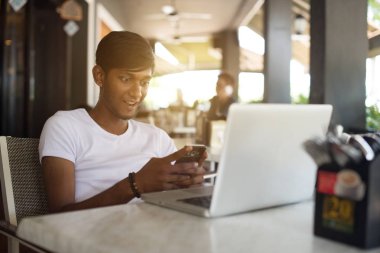 Smartphone ve dizüstü bilgisayar kullanan adam