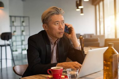 kafede dizüstü bilgisayar ve telefon kullanarak Asya kıdemli erkek