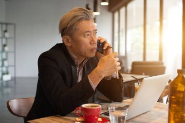 kafede dizüstü bilgisayar ve telefon kullanarak Asya kıdemli erkek