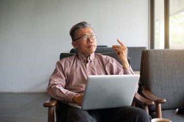 asian senior man using laptop in modern light interior clipart
