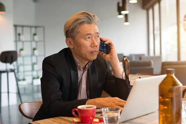亚洲高级男性使用手提电脑和电话在咖啡馆 — 图库照片