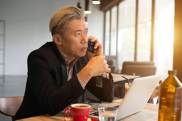 亚洲高级男性使用手提电脑和电话在咖啡馆 — 图库照片