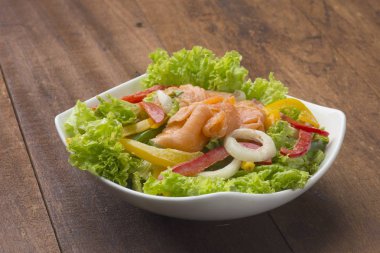 ahşap masa üzerinde beyaz tabak içinde somon salata füme 
