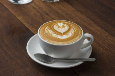 Tahta masada bir fincan sıcak latte sanat kahvesi.