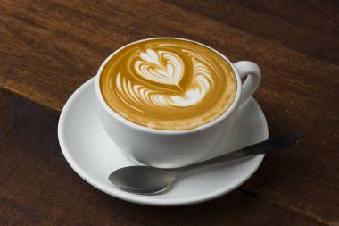 Tahta masada bir fincan sıcak latte sanat kahvesi.