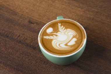 Tahta masada bir fincan sıcak latte sanat kahvesi.