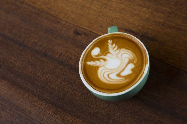 Tahta masada bir fincan sıcak latte sanat kahvesi.