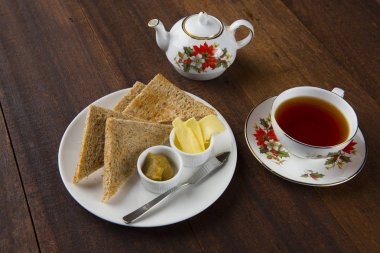 tereyağı ve ahşap masa üzerinde çay tost 