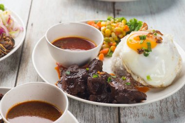 sığır eti rendang pirinç ahşap yüzey üzerinde beyaz tabakta servis