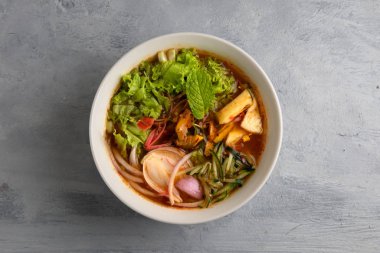 laksa erişte çorbası ve gri arka plan.