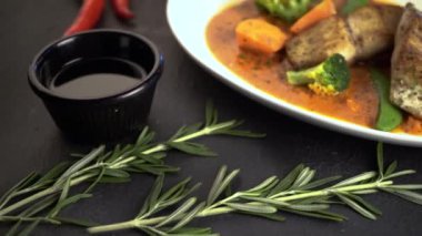 Beyaz tabakta balık bifteği ve sebzelerin yakın çekim görüntüleri.