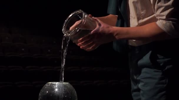En man hälla vatten från potten i skålen — Stockvideo