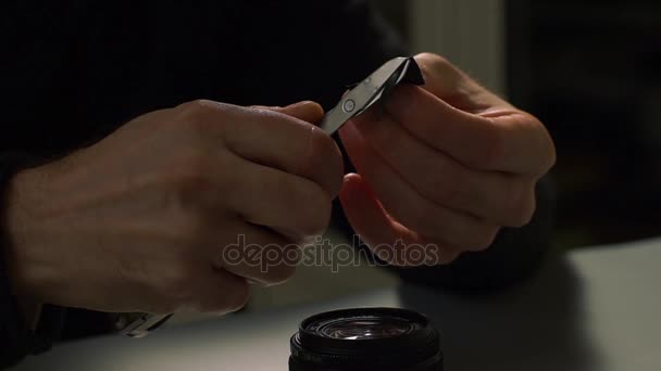 Mains masculines coupant du ruban adhésif et le collant sur l'objectif 