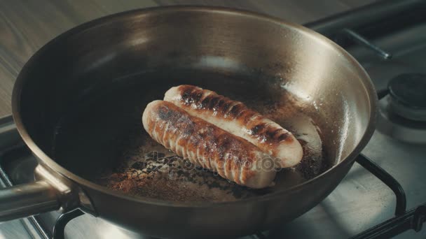 Sausages cooking and sizzling in a frying pan — Stock Video