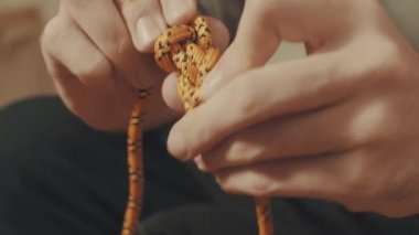 Adamın elinde bir ip üzerinde bir dağcılık düğüm tying