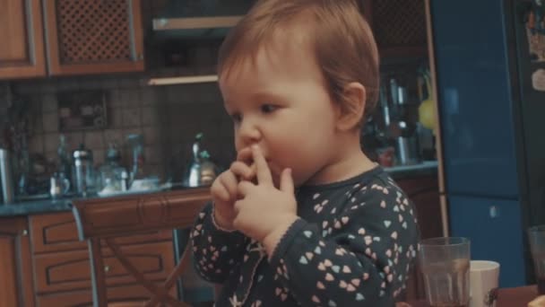 Małe dziecko siedzi na stole i jedzenie biscuit — Wideo stockowe