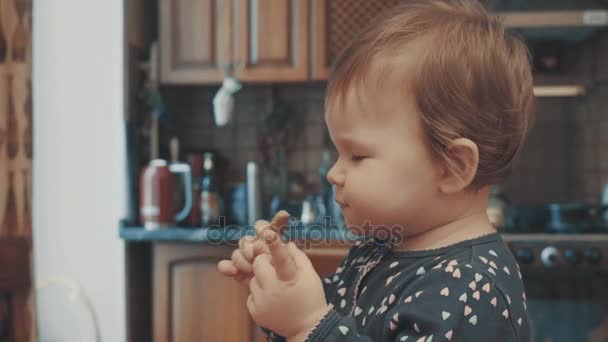 Kis baba ül a asztal és étkezési keksz — Stock videók