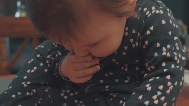 Маленький ребенок сидит на столе и ест крошки печенья — стоковое видео