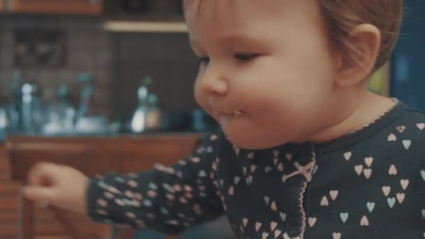 Kleine baby zittend op de tafel en eten cookie kruimels — Stockvideo