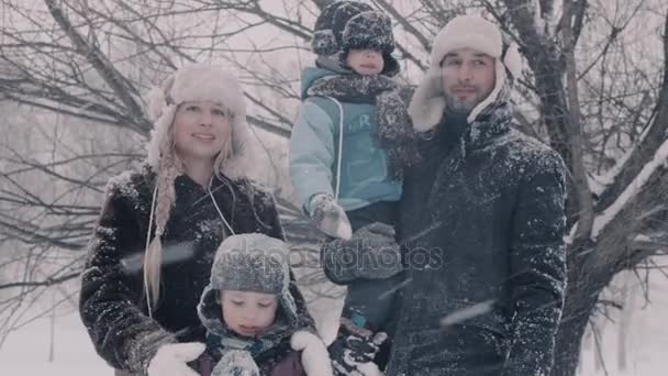 Familie staande onder sneeuwval. Twee jongens en hun ouders. — Stockvideo