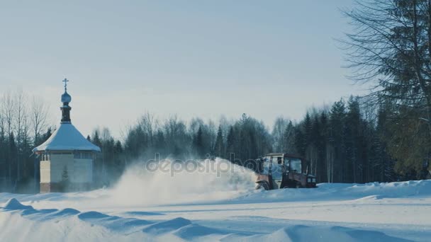 Tractor conduciendo hacia atrás y quitando la nieve de la carretera de invierno — Vídeos de Stock