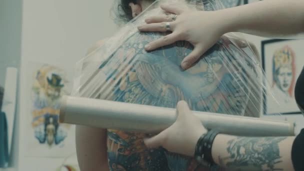 Tattooist covering tattoo with plastic film — Stock Video