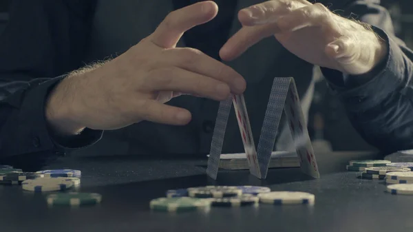 Mãos de homem construindo uma casa de cartas de jogo — Fotografia de Stock
