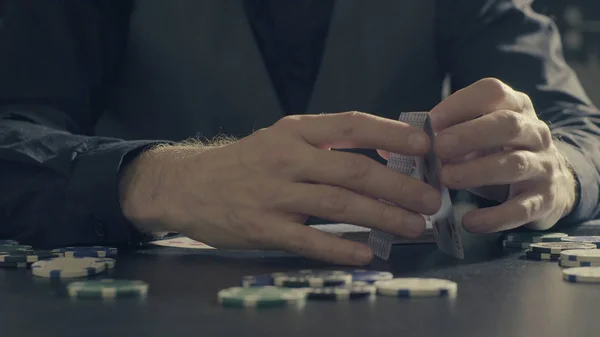 Die Hände eines Mannes, der ein Kartenhaus baut — Stockfoto