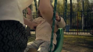 Avluda bir salıncak üzerinde bir çocuk sallanan anne