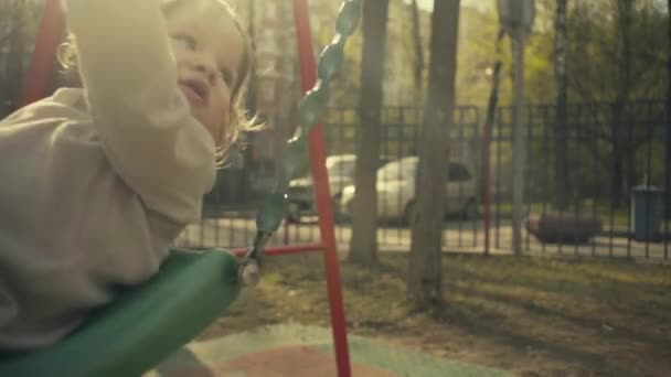 Moeder een kind op een schommel in de binnenplaats swingen — Stockvideo