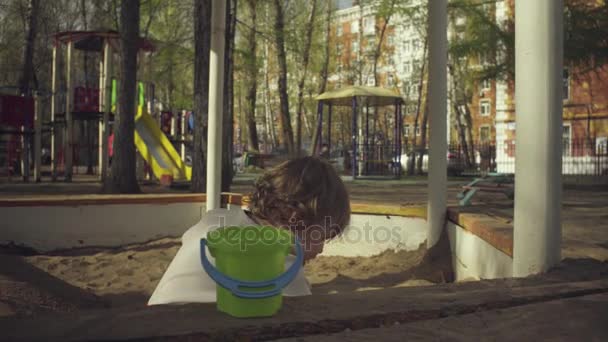 Un niño jugando en una caja de arena — Vídeo de stock