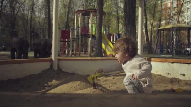 Um miúdo a brincar numa caixa de areia — Vídeo de Stock