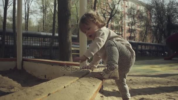 Дитина намагається залізти в пісочницю — стокове відео
