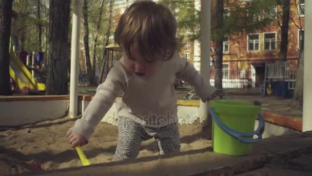 Egy gyerek játszik a homokozóban — Stock videók