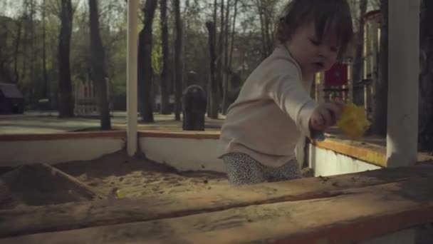 Um miúdo a brincar numa caixa de areia — Vídeo de Stock