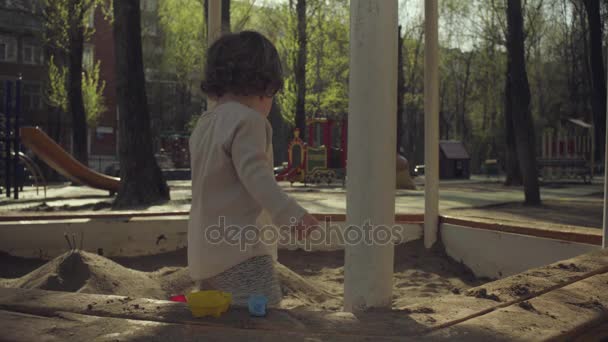 Un niño jugando en una caja de arena — Vídeo de stock