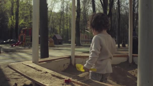 Um miúdo a brincar numa caixa de areia — Vídeo de Stock