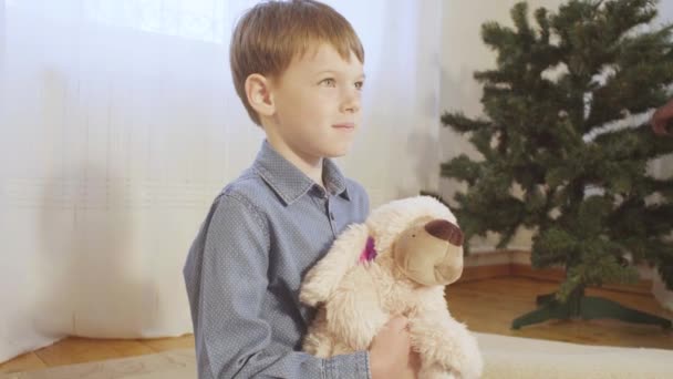 Un niño en el suelo cerca del árbol de Navidad — Vídeos de Stock