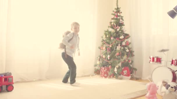 Ένα αγόρι με μια τσάντα παιχνίδι κοντά στο χριστουγεννιάτικο δέντρο — Αρχείο Βίντεο