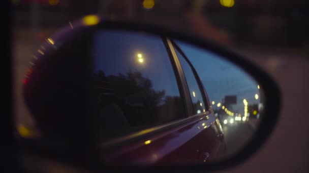 Розфокусовані міські вогні вночі у дзеркалі заднього виду — стокове відео