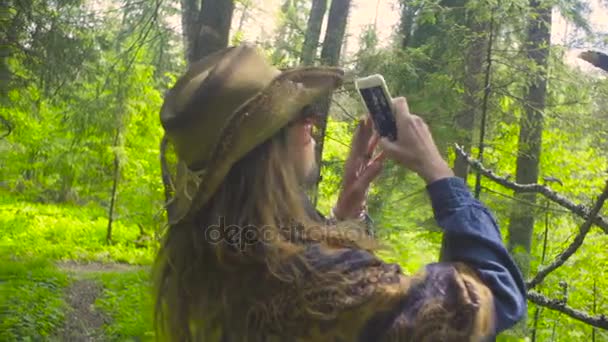 Молодая женщина в лесу фотографирует — стоковое видео