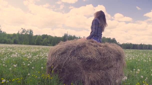 Молода жінка біжить і стрибає на стосі сіна — стокове відео
