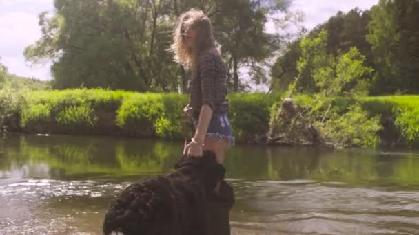 Junge Frau mit Hund spaziert durch den Fluss — Stockvideo