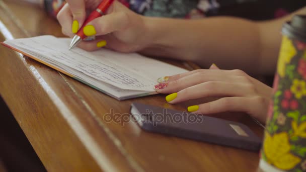 Mujeres manos escribiendo algo en un cuaderno — Vídeos de Stock