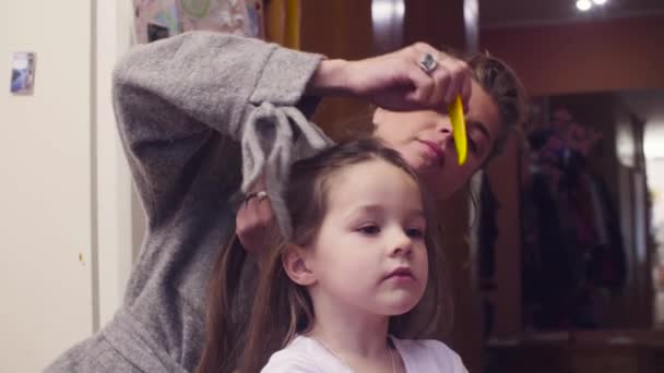 Ung kvinna kamning flickor håret — Stockvideo