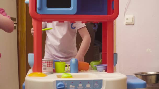 Маленька дівчинка грає з посудом і їжею — стокове відео