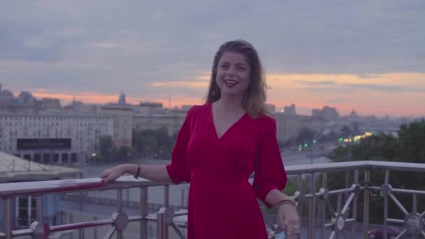 Jeune femme en robe rouge marche près de parapet — Video