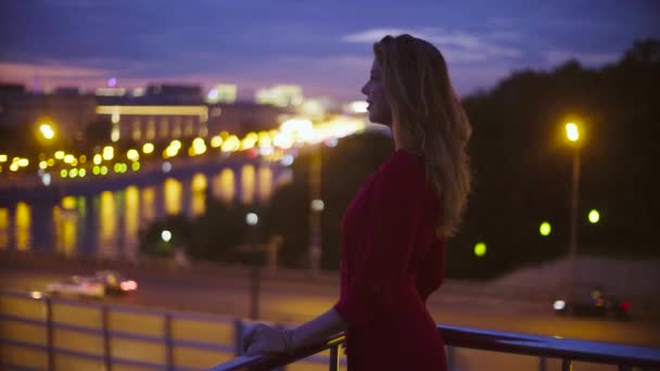 Giovane donna in abito rosso è in piedi vicino parapetto — Video Stock